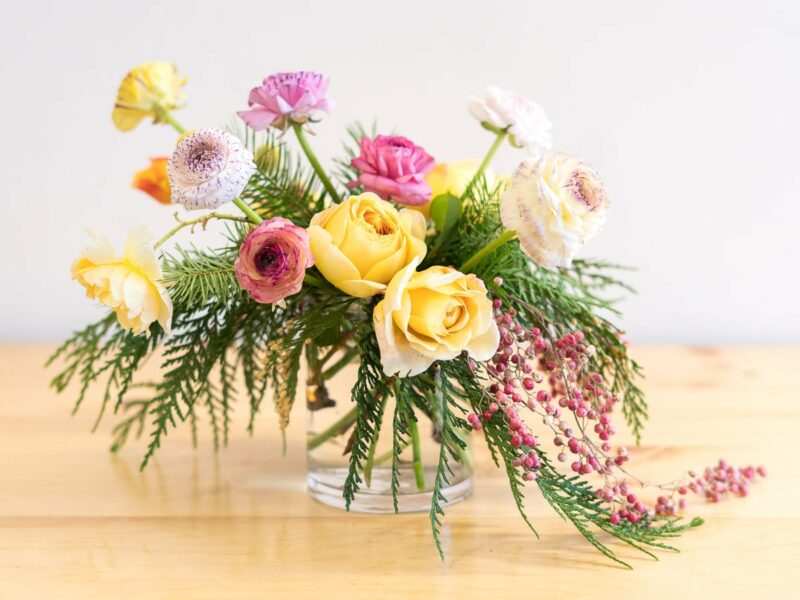 Merry & Bright flower arrangement featuring roses and ranunculus.