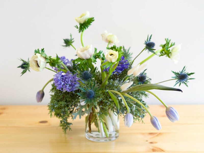 Flower arrangement with blue seasonal flowers including anemones and thistle